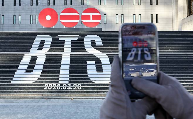 A tourist takes a photo of a promotional installation for boy band BTS's comeback in front of the Sejong Arts Center in Jongno District, central Seoul, on Jan. 22. [NEWS1]