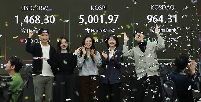 22일 오전 서울 중구 하나은행 본점 딜링룸 현황판에 코스피 지수가 장중 5000P를 넘으며 개장하자 직원들이 환호하고 있다. [뉴스1]