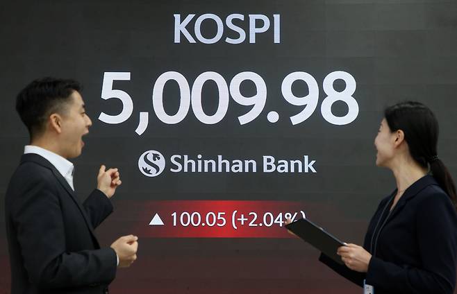 코스피가 장중 5,000을 넘어선 가운데 22일 서울 중구 신한은행 본점 로비에서 딜러들이 미소 짓고 있다. /연합뉴스