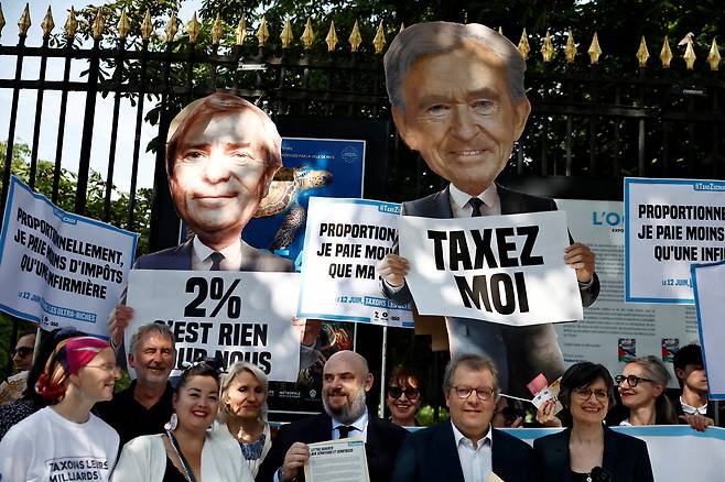 프랑스 상원에서 좌파 진영이 초부유층 대상 부유세 법안을 논의하던 지난해 6월 파리 상원 인근에서 시민단체 활동가들이 ‘부자를 과세하라’는 구호가 적힌 피켓과 프랑스 재벌인 베르나르 아르노 루이비통모에헤네시(LVMH) 회장 겸 최고경영자(CEO)와 뱅상 볼로레 볼로레그룹 명예회장을 형상화한 판넬을 들고 시위를 벌이고 있다. /로이터=연합뉴스