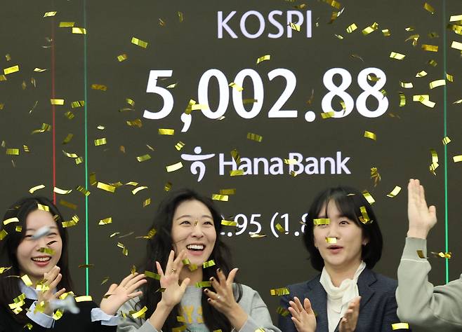 People celebrate as the Kospi surpasses the 5,000 mark for the first time at a Hana Bank in Jung District, central Seoul, on Jan. 22. [YONHAP]