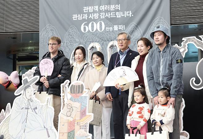 Visitors marking the National Museum of Korea’s 6 millionth annual attendance pose for a commemorative photo with Director General Yoo Hong-jun at the Uteum Hall of the museum’s permanent exhibition wing in Yongsan District, central Seoul, on Dec. 11, 2025. The milestone marked the first time the National Museum of Korea surpassed 6 million visitors in a single year. [KIM KYOUNG-ROK]
