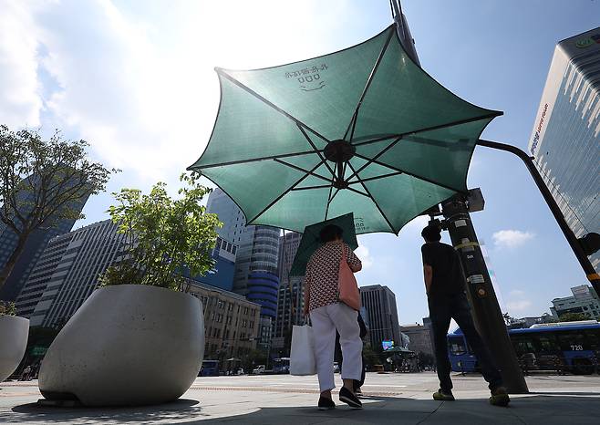 People seek shade to avoid the sun at Gwanghwamun Square in Jongno District, Seoul, on Aug. 5, 2025, amid a heat wave. [YONHAP]
