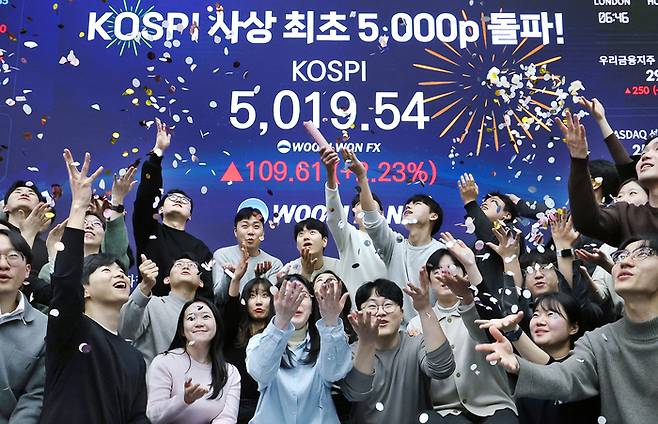 코스피가 전인미답의 5000선 고지를 밟은 22일 서울 중구 우리은행 본점 딜링룸에서 직원들이 환호하고 있다. 이날 코스피는 장중 한때 5019.54까지 상승하며 사상 처음으로 5000 고지를 돌파했다. 이후 상승폭을 줄이며 0.87% 오른 4952.53으로 장을 마쳤다. [뉴스1]