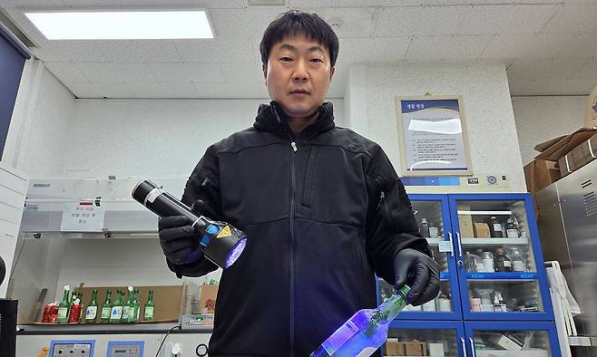 김흥주 경위가 사건현장에서 수거한 소주병에 지문 현출 분말을 묻히고 광원을 비춰 지문을 확인하고 있다.