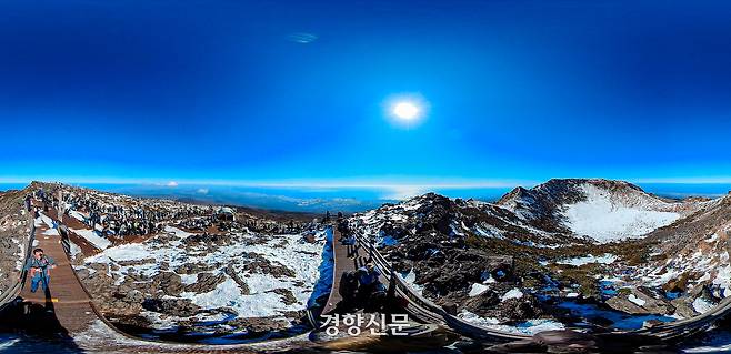 눈 내린 한라산 백록담(오른쪽)을 찾은 탐방객(왼쪽)들이 정상석 주변에서 사진을 찍거나 각자 싸 온 도시락으로 점심을 먹고 있다. 2025.11.23