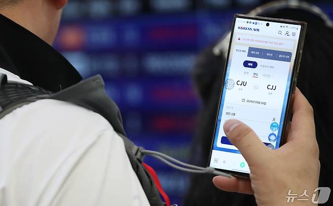 공항 출발장에서 한 승객이 휴대전화로 항공권을 검색하고 있는 모습. /뉴스1DB ⓒ News1 오현지 기자