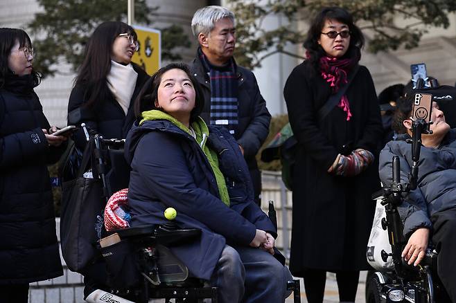 장애인 활동가 문애린(앞줄 왼쪽)씨와 비장애 활동가 한명희(뒤줄 오른쪽 끝)씨가 2026년 1월29일 서울 서초구 서울중앙지방법에서 선고공판을 마친 뒤 소감을 밝히고 있다.