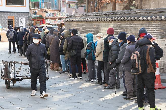 People wait in line for free meals at Tapgol Park in Nakwon-dong, Jongno District, central Seoul. [YONHAP]