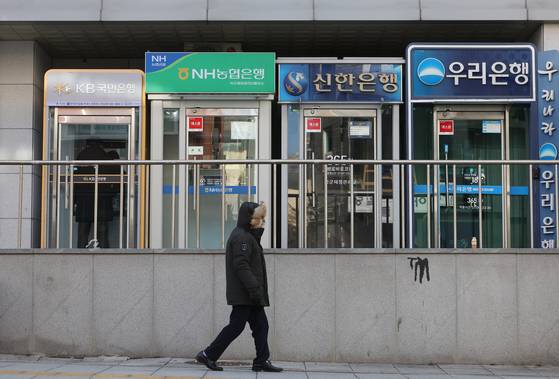 A person passes by automated teller machines from major banks in Seoul on Dec. 21, 2025. [YONHAP]