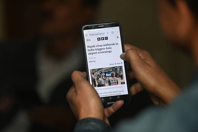 파키스탄 카라치에서 한 남성이 28일(현지시간) 인도 웨스트벵골주에서 보고된 니파 바이러스 감염 사례와 관련한 뉴스 알림을 스마트폰으로 확인하고 있다. 인도 보건당국은 이달 들어 치명적인 인수공통감염병인 니파 바이러스 확진 사례 2건을 공식 확인했으며, 추가 확산을 막기 위해 약 200명에 대한 접촉자 추적과 함께 ‘적시 차단(timely containment)’ 조치를 진행 중이라고 밝혔다.(EPA/연합뉴스)