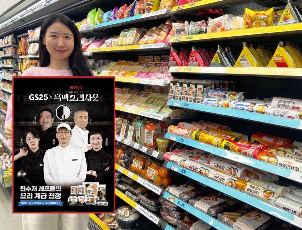 GS25에서 모델이 간편식품 진열대 앞에서 흑백요리사2 컬배버 상품 출시 안내 홍보물을 들고 있다 사진GS25