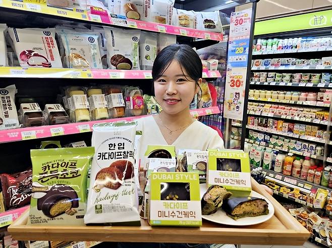 편의점 CU는 ‘두쫀쿠’ 열풍에 힘입어 ‘두바이 미니 수건 케이크’ 등 관련 신상품을 추가로 선보인다고 14일 밝혔다. 모델이 두바이 디저트를 소개하고 있다. [BGF리테일 제공]