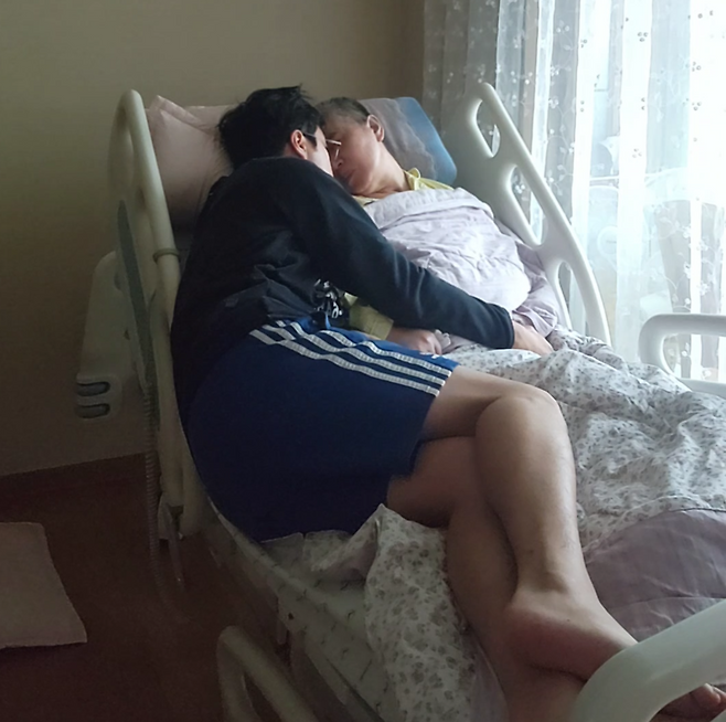 Cho Bum-hee lies on a bed with his mother. (Cho Bum-hee)