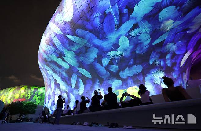 [서울=뉴시스] 조성우 기자 = 28일 오후 서울 중구 동대문디자인플라자(DDP)에서 열린 '서울라이트 DDP 2025 가을'을 찾은 시민들과 외국인 관광객들이 미디어파사드 작품을 관람하고 있다. 2025.08.28. xconfind@newsis.com