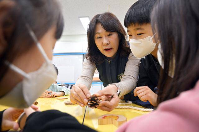 이씨가 학생들에게 솔방울을 보여주며 소나무의 씨앗이 어디에 숨겨져 있는지 설명하고 있다. 최주연 기자