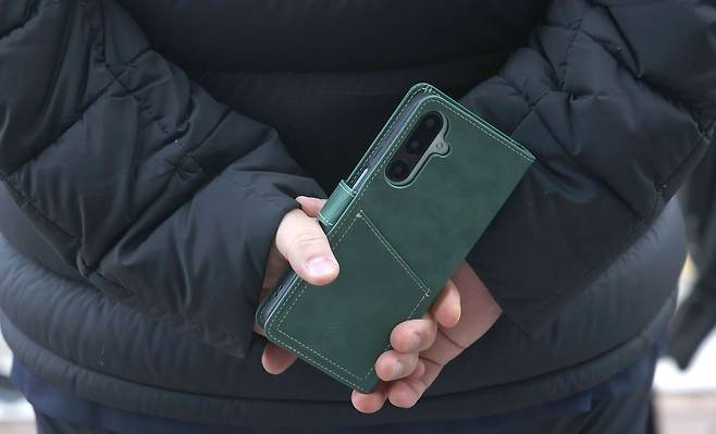 정치자금법 혐의로 기소된 정치 브로커 명태균 씨가 5일 오후 경남 창원시 성산구 창원지법에서 열린 1심 재판에서 무죄 선고를 받은 후 변호인이 취재진 질문에 답하는 동안 뒷짐을 지고 있다. 사진은 명씨 휴대전화.   명씨는 증거은닉 교사 혐의에 대해서는 징역 6개월에 집행유예 1년을 선고받았다. 연합뉴스