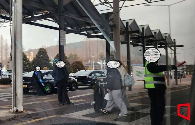 "5일 광주공항 택시 승강장 앞. 제복을 입은 교통 통제 요원(오른쪽)이 근무 중이지만, 바로 옆에서 등산복 차림의 모범택시 기사들이 버젓이 호객 행위를 하고 있다. 통제요원이 있어도 제지하지 않는 모습에 이용객들은 혼란을 겪고 있다. 박창원 기자