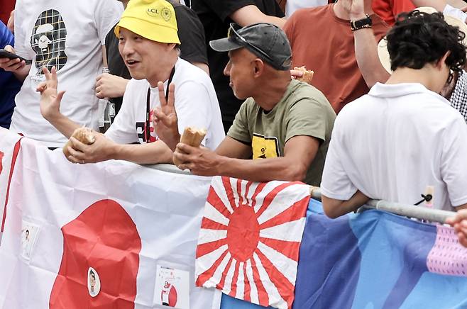 지난 2024년 파리하계올림픽 사이클 남자 도로 경기 도중 몽마르트 언덕에 한 일본인이 일장기와 나란히 일본 제국주의를 상징하는 욱일승천기를 걸어놓고 응원을 하는 모습. [올림픽사진공동취재단]