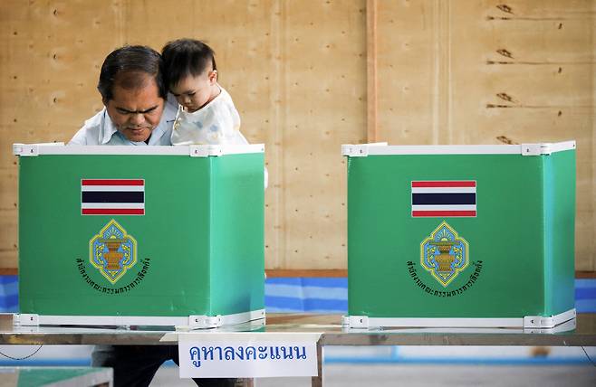 8일 태국 방콕의 투표소에서 한 유권자가 아이를 안은 채 조기 총선 투표를 하고 있다.  로이터연합뉴스