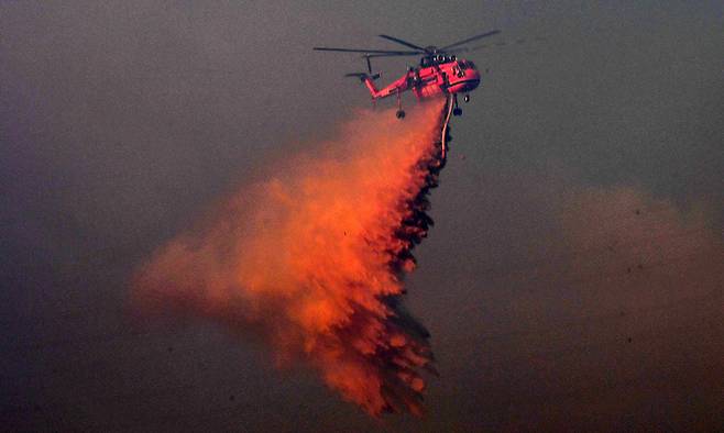 산불과 사투 중인 헬기 8일 경북 경주시 문무대왕면 입천리 일원에서 산림청 초대형 진화헬기(S-64)가 송전선로를 피해 산불 현장에 물을 뿌리고 있다. 7일 오후 9시40분쯤 발생한 산불은 순간 최대풍속 초속 21.6m 정도의 강풍 등에 힘입어 발생 지점으로부터 직선거리로 8㎞ 내외에 있는 세계유산 불국사, 석굴암 등까지 위협했다. 산림당국은 8일 오후 6시쯤 주불 진화 완료를 선언했으나 2시간여 만에 재발화해 오후 10시 기준 진화 작업이 계속 이어졌다. 경주=뉴스1
