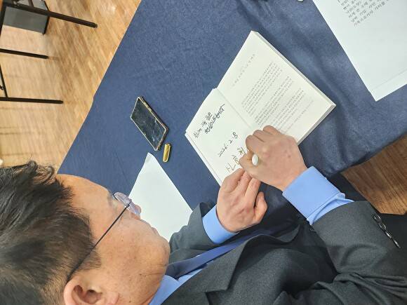 신효철 전 위원장이 책자에 사인을 하고 있다 [사진=신효철]