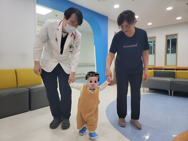 김하늘(가명) 군이 4일 강원대병원 어린이병동 휴게실에서 박진성 강원대병원 소아청소년과 과장과 양미영 간병인의 손을 잡고 걷고 있다. 이설화 기자