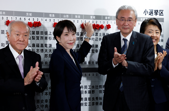 다카이치 사나에 일본 총리(왼쪽 두번째)가 8일 중의원 선거(총선)에서 승리한 당선자 리스트에 당선을 의미하는 붉은 장미를 달아주고 있다. [로이터 연합뉴스]