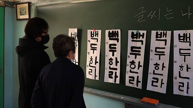홍순관(사진 왼쪽)이 2022년오카야마조선학교 서예 교사와 함께 학생들 작품을 감상하고 있다. 홍순관 제공