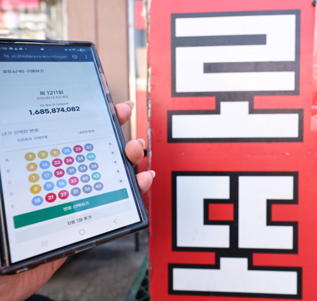 서울 시내의 한 복권 판매점 앞에서 시민이 휴대폰으로 로또를 구매하고 있다. 뉴스1