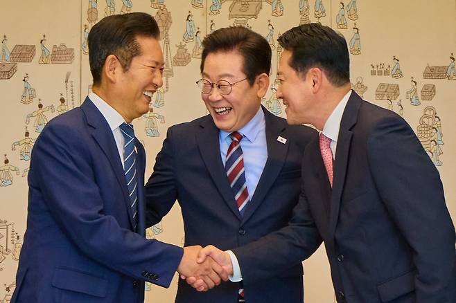 이재명 대통령이 작년 9월 8일 용산 대통령실에서 열린 여야 지도부 오찬 회동에서 정청래 더불어민주당 대표, 장동혁 국민의힘 대표가 악수하는 것을 보며 미소짓고 있다./뉴스1