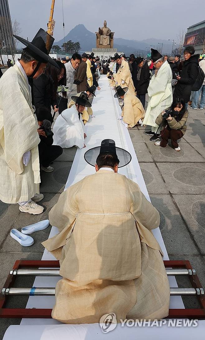 광화문에 등장한 대형 상소문 (서울=연합뉴스) 한종찬 기자 = 11일 서울 광화문광장에서 열린 제8차 영남만인소 봉소 재현 행사에서 참가자들이 길이 100m가 넘는 대형 상소문을 펼쳐보이고 있다. 이날 이들은 독립운동가 20인에 대한 서훈의 전면 재평가와 승격을 정부에 촉구했다. 2026.2.11 saba@yna.co.kr