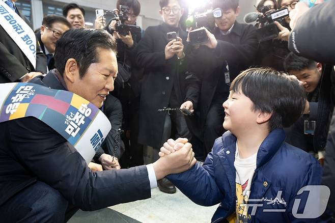 정청래 더불어민주당 대표가 13일 서울 용산역에서 설 귀성객 인사를 하며 아이와 팔씨름을 하고 있다. 2026.2.13 ⓒ 뉴스1 이승배 기자