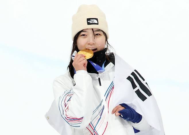 12일(현지 시각) 이탈리아 리비뇨 스노파크에서 열린 2026 밀라노·코르티나담페초 동계올림픽 스노보드 여자 하프파이프 결선에서 90.25점을 받아 금메달을 획득한 스노보드 최가온이 금메달을 깨물며 기뻐하고 있다./뉴스1