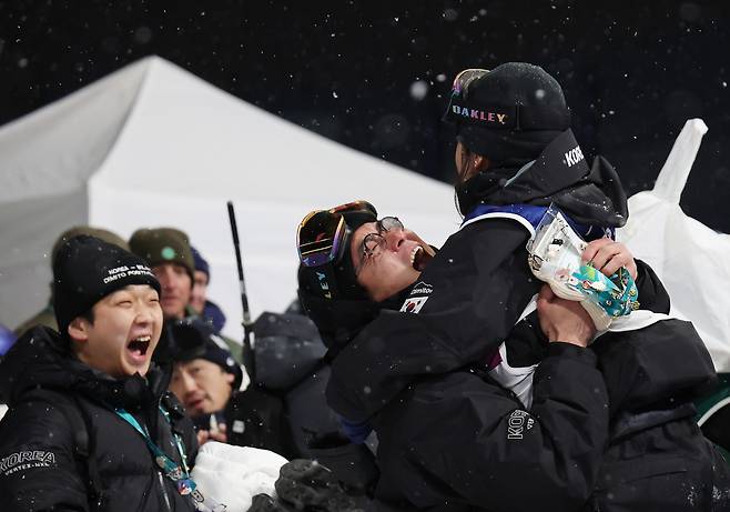 “금이래요.” 13일 이탈리아 리비뇨 스노파크에서 열린 2026 밀라노-코르티나 동계올림픽 스노보드 여자 하프파이프 결승에서 최가온이 금메달을 확정짓고 팀 관계자들과 기뻐하고 있다. [연합]
