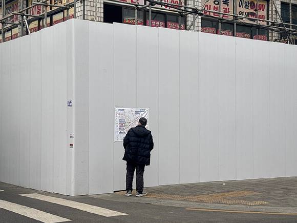 2월 10일 강북구 번동 강북구청 철거현장에서 한 시민이 강북구청 공사도를 유심히 보고있다. [사진=김민지 기자]