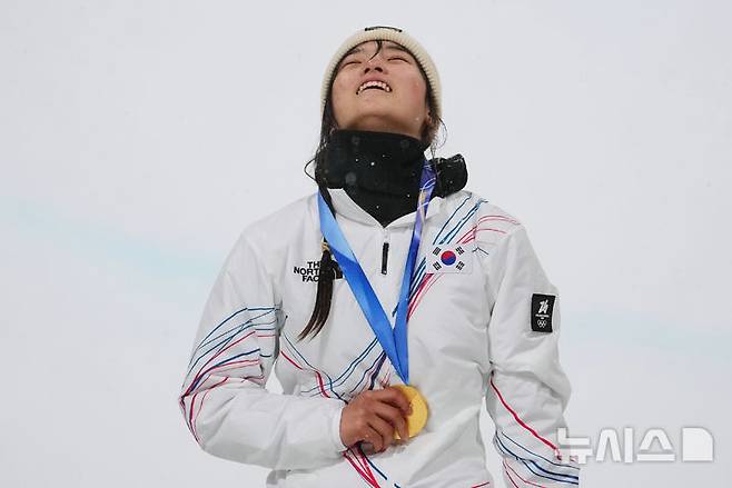 [리비뇨=AP/뉴시스] 최가온이 12일(현지 시간) 이탈리아 리비뇨 스노파크에서 열린 2026 밀라노·코르티나담페초 동계올림픽 스노보드 여자 하프파이프 정상에 올라 금메달을 목에 걸고 웃음 짓고 있다. 최가온은 1차 시기에서 크게 넘어져 충격을 안겼으나 3차 시기에서 90.25점을 획득해 강력한 우승 후보 클로이 김을 제치고 정상에 올랐다. 최연소 금메달 기록도 갈아치운 그는 시상식 도중 애국가가 흘러나오자, 끝내 눈물을 흘렸다. 2026.02.13.