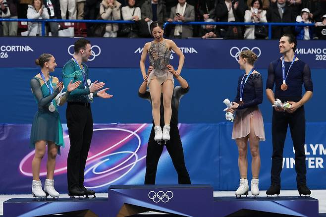 기하라 류이치가 17일 이탈리아 밀라노 아이스 스케이팅 아레나에서 열린 2026 밀라노·코르티나담페초 동계 올림픽 피겨 스케이팅 페어 프리 스케이팅 시상대에서 미우라 리쿠를 번쩍 들어올리며 고마움을 표시하고 있다. AP연합뉴스