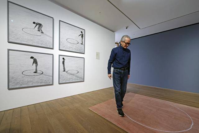 이건용이 4일 서울 용산구 페이스갤러리 서울에서 개인전 '사유하는 몸' 기자간담회에 앞서 1975년에 선보인 행위 예술 '장소의 논리'를 재연하고 있다. 자신이 분필로 그린 원 경계를 돌면서 "어디, 어디, 어디"를 반복했다. 왼쪽 사진은 1975년 당시 홍익대 운동장에서 '장소의 논리'를 촬영한 것이다. 뉴시스