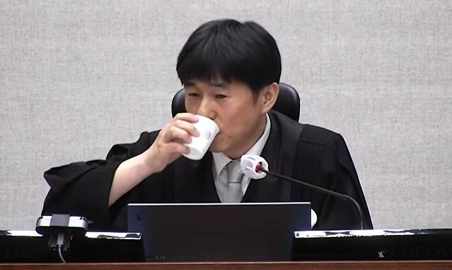 지귀연 재판장이 19일 오후 서울 서초동 서울중앙지법 417호 형사대법정에서 내란 우두머리 혐의로 구속 기소된 윤석열 전 대통령 등에 대한 판결 이유를 설명하던 중 물을 마시고 있다. 서울중앙지법 재판 생중계 화면 갈무리