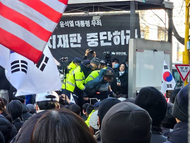 19일 오후 서울 서초구 서울중앙지법 인근에서 한 남성이 설치된 무대 위로 난입해 경찰이 제지에 나섰다./사진=박상혁 기자.