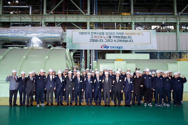 [서울=뉴시스] 김성환 기후에너지환경부장관이 31일 충남 태안군 소재 한국서부발전본부에서 열린 태안석탄화력발전소 1호기 발전종료 행사를 마치고 발전소 직원들과 함께 1호기를 배경으로 기념촬영을 하고 있다. (사진=기후에너지환경부 제공). 2025.12.31. photo@newsis.com *재판매 및 DB 금지