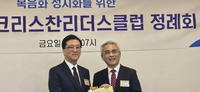 이희학 대표회장이 신입회원인 조원휘 대전시의장에게 성경책을 선물하고 있다.