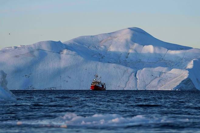 지난달 29일(현지 시간) 그린란드 일룰리사트 인근 디스코만에서 어선 한 척이 빙산 앞에서 그물을 끌어 올리며 어획한 물고기를 건지고 있다. AP·뉴시스