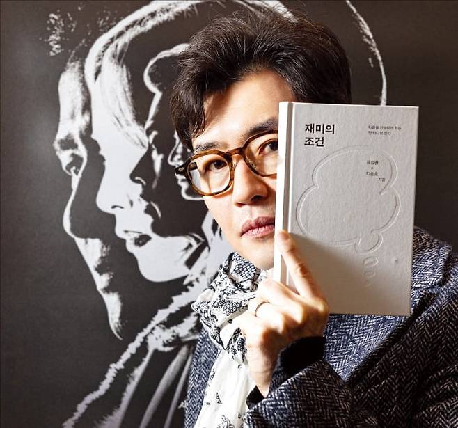 영화 ‘휴민트’ 포스터 앞에서 자신의 저서 <재미의 조건>을 들고 있는 류승완 감독. /박충열