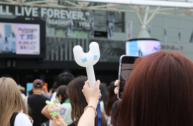 Fans take pictures of the K-pop goods of girl group NewJeans before a meet and greet event held on June 27, 2024, at the Tokyo Dome in Japan. [YONHAP]