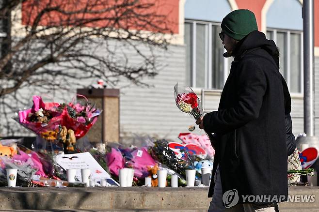 총기난사 피해자 추모공간 한 남성이 지난 14일(현지시간) 캐나다 브리티시컬럼비아주 텀블러리지 시청 계단에 마련된 총기난사 사건 임시 추모 공간에 헌화하고 있다. [로이터=연합뉴스 자료사진. 재판매 및 DB 금지]