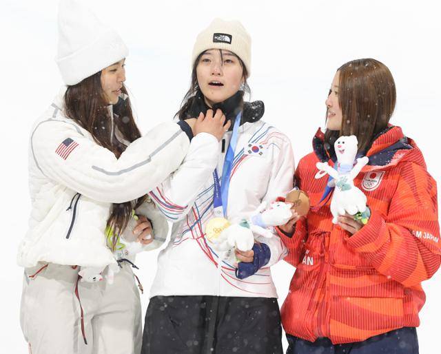 12일(현지시간) 이탈리아 리비뇨 스노파크에서 열린 2026 밀라노·코르티나담페초 동계 올림픽 스키 스노보드 여자 하프파이프 결선에서 은메달을 획득한 미국의 클로이 김이 사진 촬영 전 얼굴을 가린 최가온의 목도리를 내려주고 있다. 리비뇨=연합뉴스