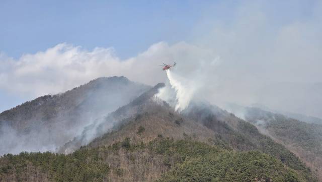 함양 산불 현장에서 소방헬기가 공중에서 물을 투하하며 진화 작업을 벌이고 있다.
