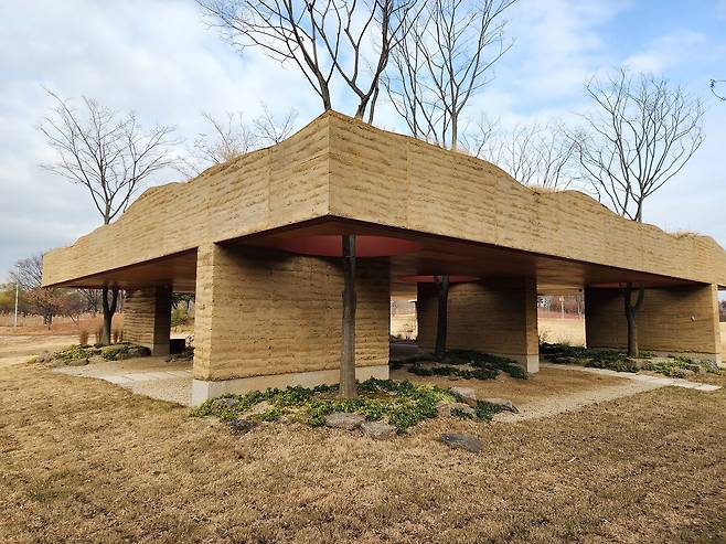 벽과 지붕으로만 이루어진 상암동 노을공원의 ‘새로운 지층’. 나무·억새·하늘을 담는 액자 같은 건물이다. [사진 조성익]